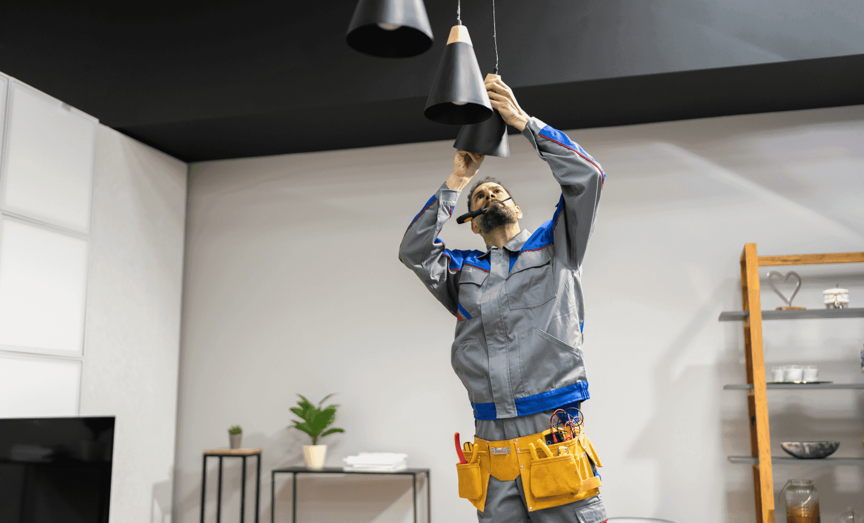 Electrician fixing ceiling lights indoors.